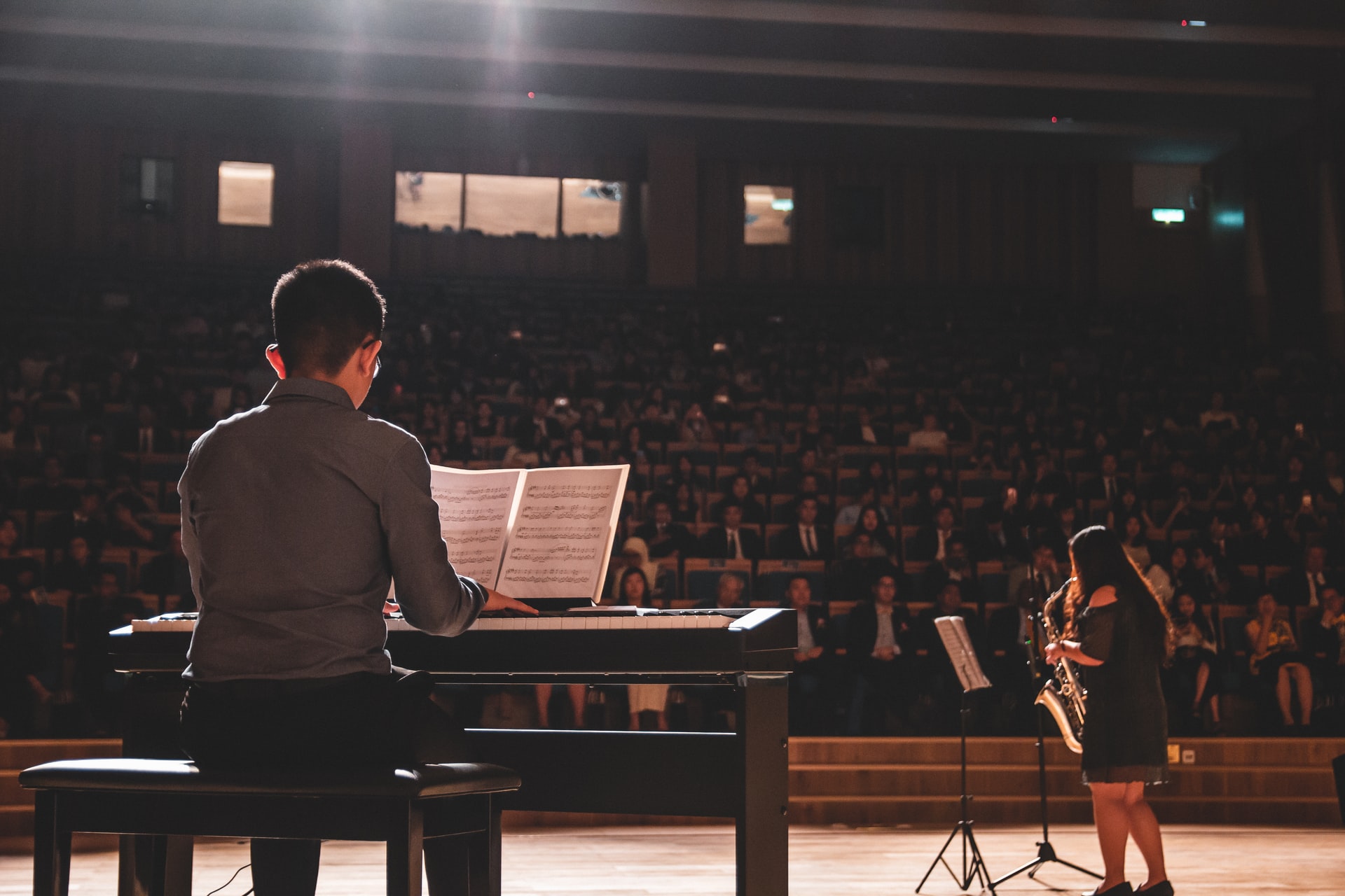 Students playing piano and saxaphone infront of audience